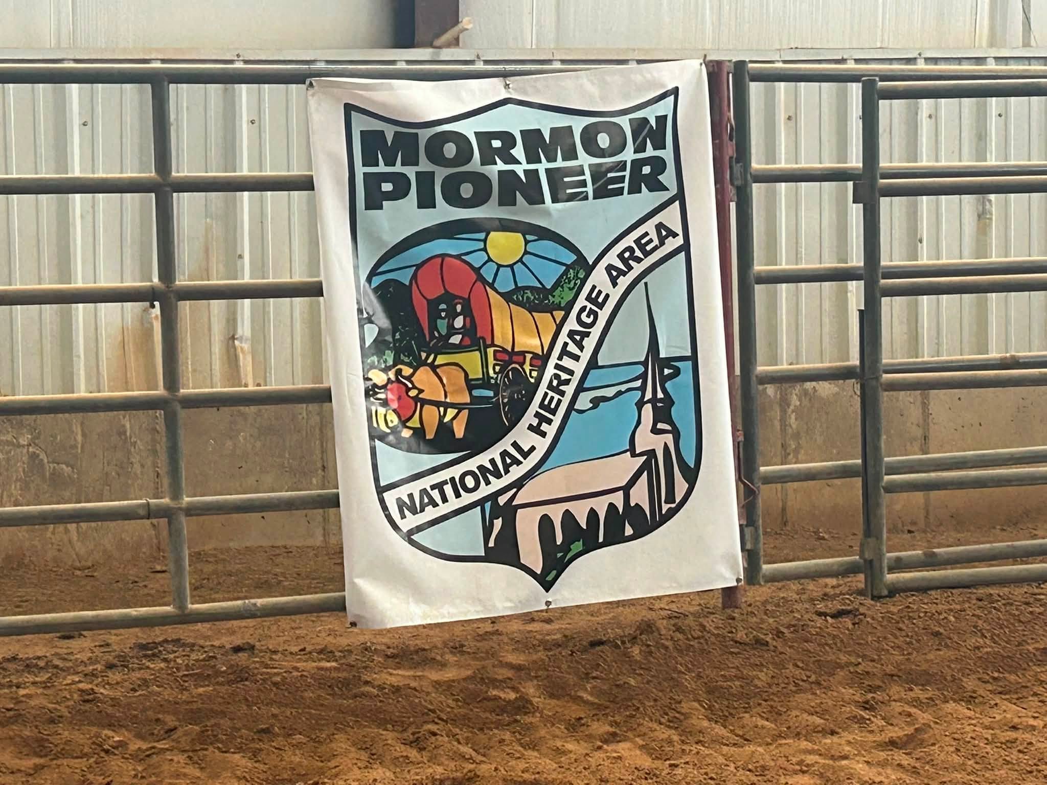 Mormon Pioneer National Heritage Area banner attached to indoor arena fencing.