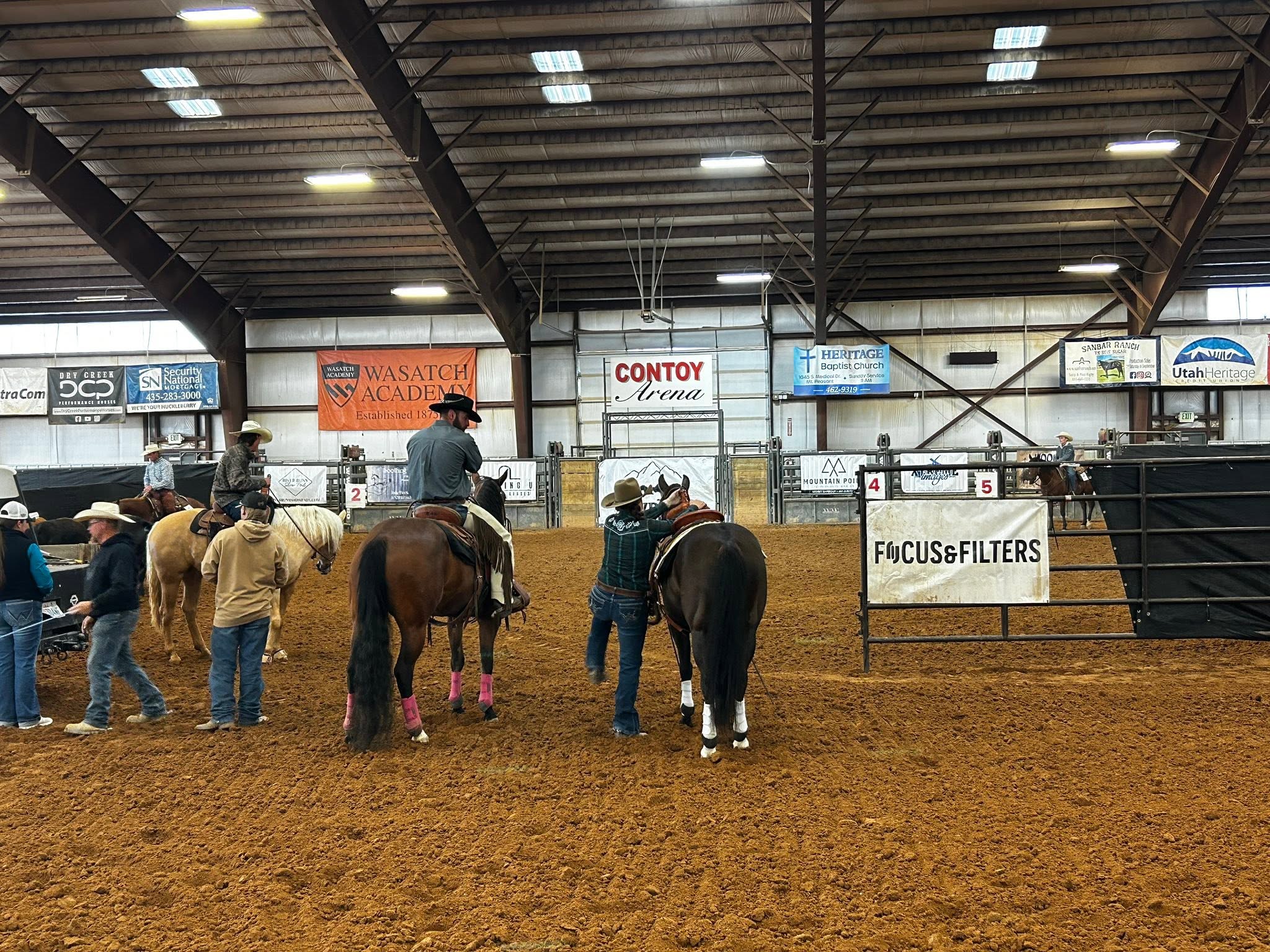 Riders and handlers on the indoor arena dirt floor at Contoy Arena.