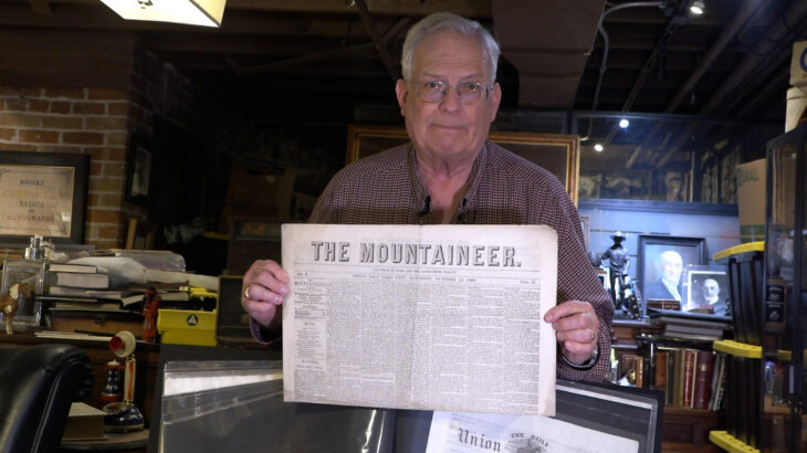 Man holding newspaper from early Utah Settlements
